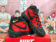 Angled view of the pair highlighting the red side panels, black overlays, yellow accents, and thick outsole.