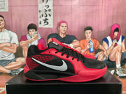 Side profile of a red and black Nike basketball sneaker showing the Swoosh logo, patterned side panel, and sculpted midsole.