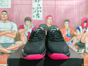 Front view of black and grey Jordan basketball sneakers with bright red-pink outsoles on a shoebox.
