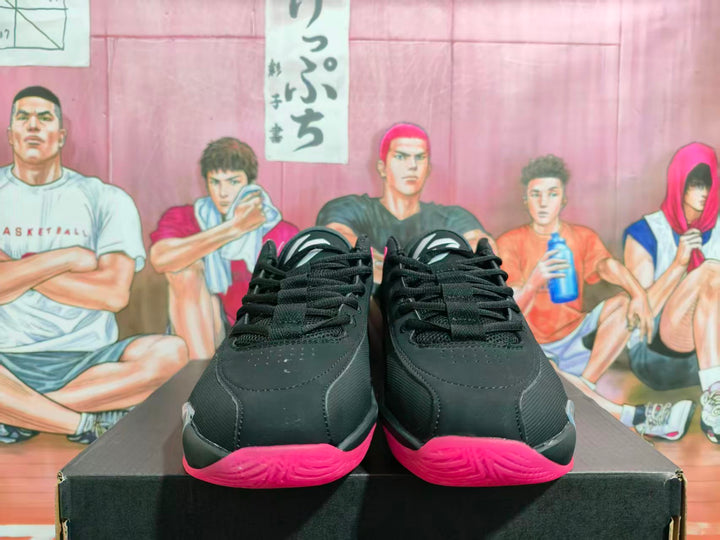 Front view of black and grey Jordan basketball sneakers with bright red-pink outsoles on a shoebox.