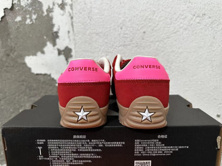 Rear view of red and pink Converse low-top sneakers with tan soles and star-shaped heel details.