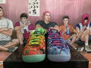 Front view of the mismatched sneaker pair showing orange-green and blue patterned uppers with bright contrasting laces.