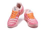 Front three-quarter view of pink Nike sneakers with bright orange laces and patterned uppers.