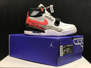 Side view of a white, black, coral, and grey Jordan Legacy 312 sneaker resting on a purple shoe box; the box label is visible.