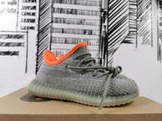 Side view of the gray low-top sneaker with orange collar lining and translucent ribbed sole on a shoebox.