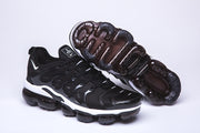 Black and white Nike TN-10 sneaker beside an upturned shoe showing its segmented sole.