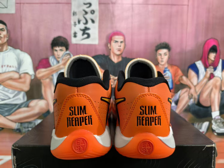 Rear view of orange and black sneakers showing black collars, white midsoles, orange outsoles, and “SLIM REAPER” heel lettering.