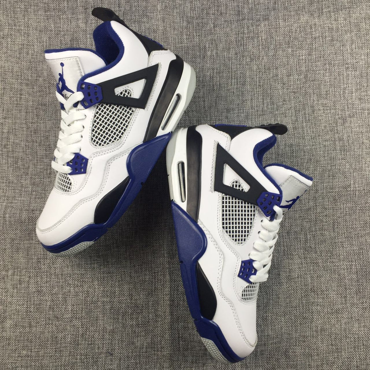 Pair of white, black, and blue Jordan Air Jordan 4 sneakers shown from an angled top view.