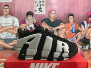 Side profile of a black and grey Nike sneaker showing the layered upper, contrasting panels and segmented sole.