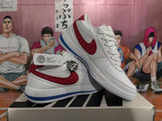 Angled view of the white sneakers showing red Swoosh branding, heel details, and blue outsole accents.