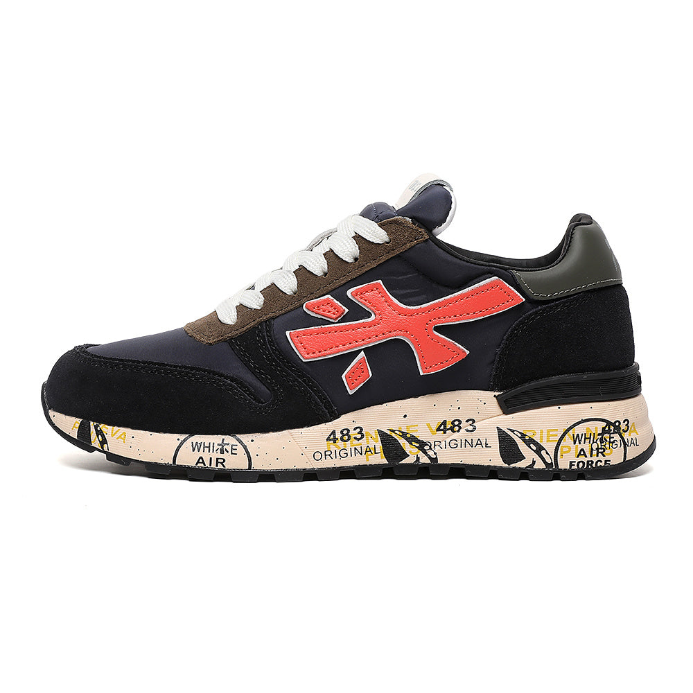Side view of a navy and black low-top Premiata sneaker with white laces, a red side logo, brown lace panel and cream graphic-print sole.