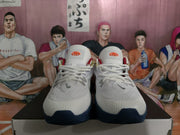 Front view of a pair of white Nike basketball sneakers showing the tongue logos, laces, and navy toe outsole sections.
