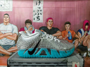 Pair of silver Nike basketball sneakers with black Swoosh branding and translucent turquoise soles on a box.
