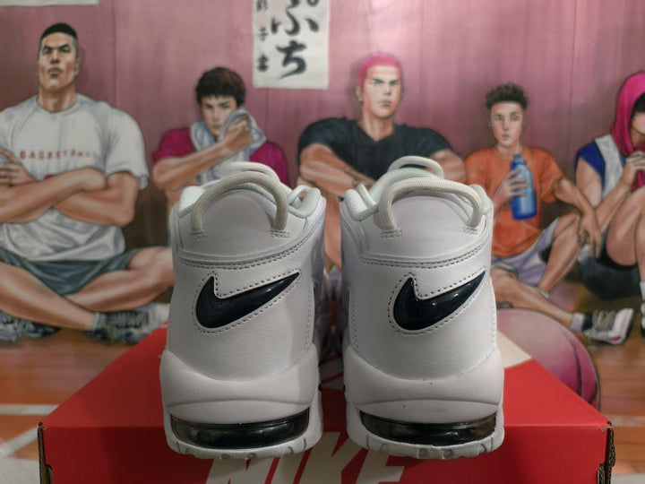 Rear view of white Nike sneakers with dark navy Swoosh accents and visible Air cushioning windows, displayed on a red Nike shoebox.
