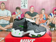 Side view of a Nike sneaker showing layered gray and black panels, fluorescent green accents, white sculpted midsole, and visible sole elements.