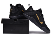 Black and gold basketball shoes displayed on and beside a black box