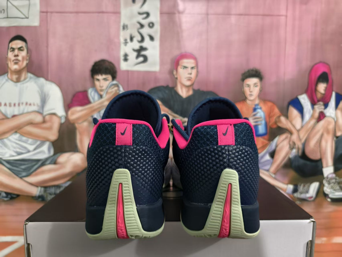 Rear view of dark navy Nike basketball sneakers with pink heel accents and pale green outsole details, placed on a shoe box.