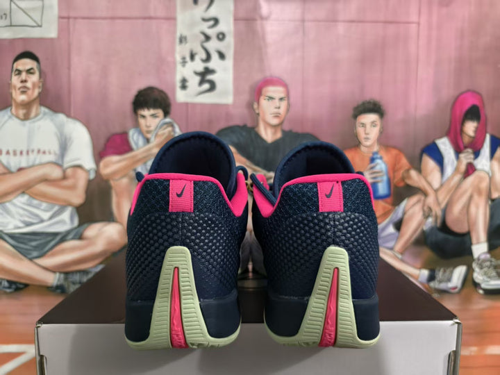 Rear view of dark navy Nike basketball sneakers with pink heel accents and pale green outsole details, placed on a shoe box.