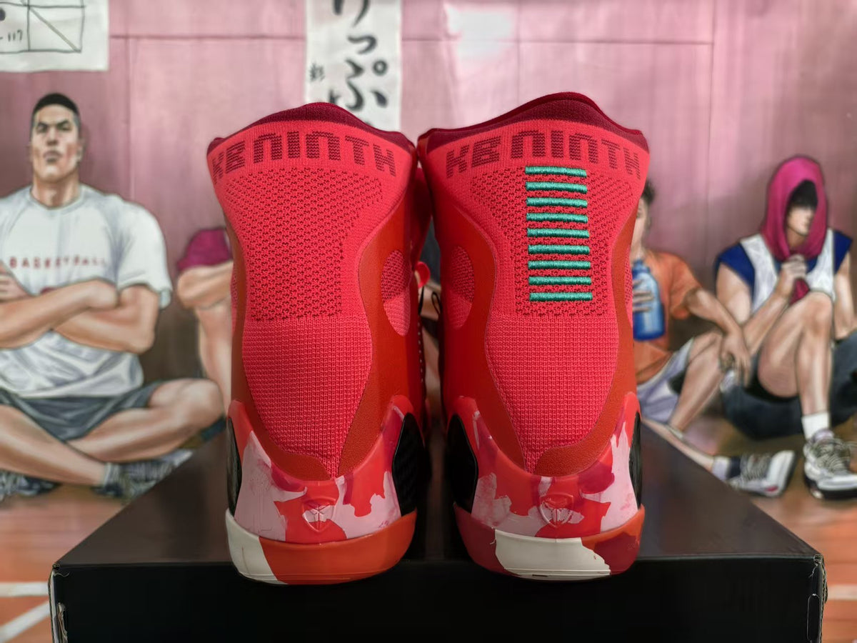 Rear view of red high-top basketball sneakers showing knit-style collars, green accent stitching, patterned heel panels, and contrasting midsoles.