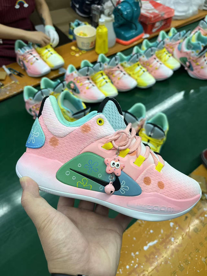 Close-up of a pink and yellow Nike Hyperdunk-style sneaker with turquoise accents and character-themed decorations