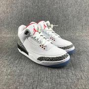 Pair of white Jordan Air Jordan 3 sneakers viewed from the front, showing red tongue accents, white laces, and elephant-print toe overlays.