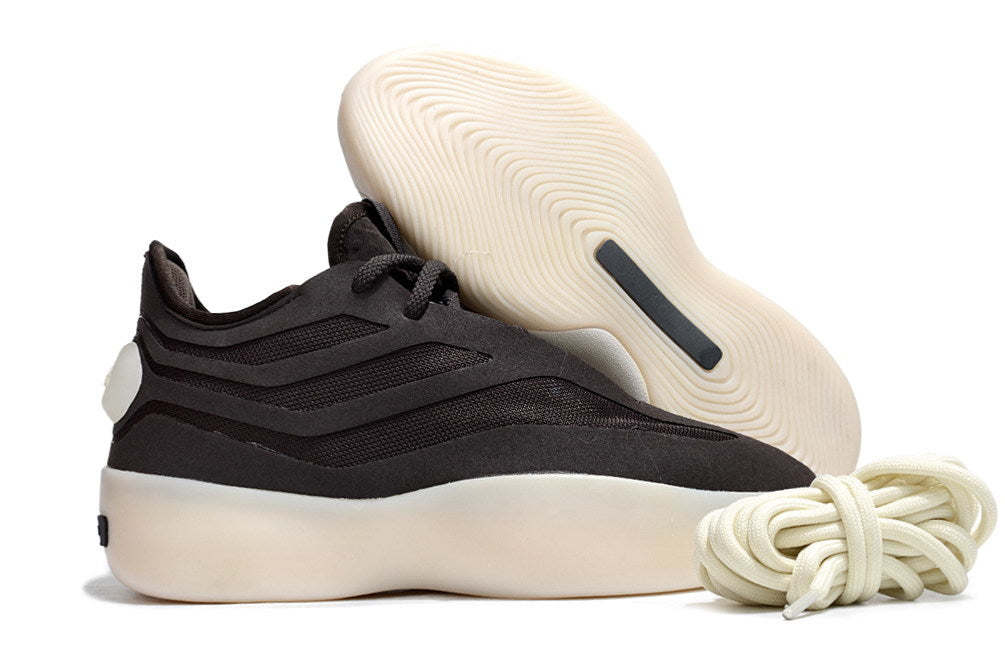 Black low-top sneaker shown from the side with its cream outsole raised behind it and coiled laces in front.
