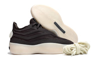Black low-top sneaker shown from the side with its cream outsole raised behind it and coiled laces in front.