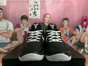 Front view of the pair displaying the textured black uppers, white laces, and white toe outsoles.