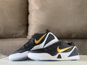 Pair of black Nike Kobe 9 sneakers with gold Swooshes shown from a three-quarter angle.