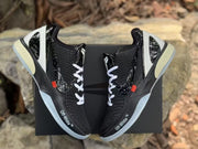 Top-down view of the sneaker pair with white laces, black textured uppers, white heel structures, and light-colored outsole sections.