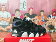 Side profile of the black Nike Air sneaker showing perforated panels, white outsole sections, and a visible translucent heel unit.