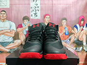 Front view of the pair showing black uppers, red Under Armour tongue logos, and red traction outsoles.