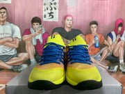 Front view of yellow and blue Nike sneakers with blue laces, orange lace accents, and black outsoles.