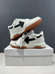 Angled view of the white low-top sneakers showing the layered upper, black arrow panels, and gum outsole.