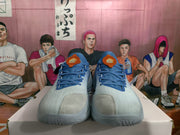 Front view of blue low-top sneakers with blue laces, gray toe panels, and orange tongue labels.