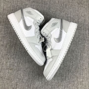 Pair of white and silver high-top sneakers arranged diagonally on a gray fabric surface.
