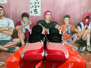 Front view showing the pink toe boxes, red toe overlays, black laces, and textured red outsoles.