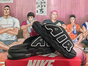 Angled view of black slides displaying the AIR strap lettering, layered sole, and cushioned construction.