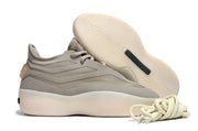 Brown-gray sneaker shown from the side with its cream outsole raised behind it and coiled laces in front.