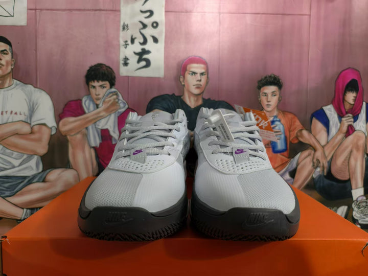 Front view of gray and white Nike Giannis Immortality basketball shoes with purple lace-tab logos.
