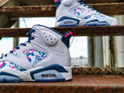 Side view highlighting the perforated white upper, multicolor patterned panels, blue midsole accents, and visible heel air unit.