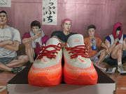 Front view of the pair of white and bright orange basketball shoes with red laces.