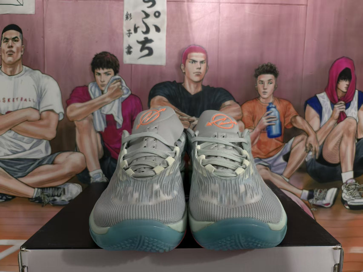 Front view of grey-blue Nike basketball sneakers with orange tongue accents and translucent blue-tinted outsoles.