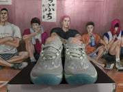 Front view of grey-blue Nike basketball sneakers with orange tongue accents and translucent blue-tinted outsoles.