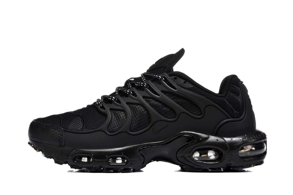 Side view of black Nike Air Max Plus-style sneakers with mesh panels, wavy side supports, and visible sole cushioning units.