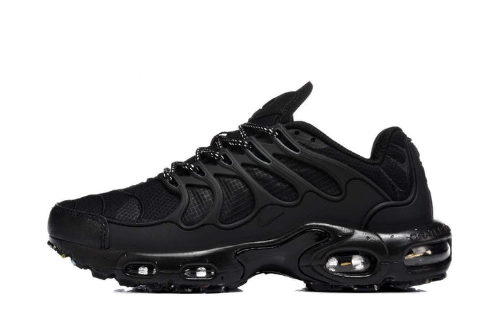 Side view of black Nike Air Max Plus-style sneakers with mesh panels, wavy side supports, and visible sole cushioning units.