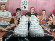 Front view of gray and white Nike basketball sneakers with textured uppers and patterned outsoles, displayed on a black box.
