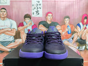 Front view showing the black mesh uppers, purple laces, tongue details, and textured purple outsoles.