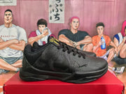 Side view of a black basketball sneaker showing layered textured panels, lace-up construction, padded collar, and low-profile sole.