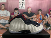Side profile of a white Nike Air Foamposite One sneaker with navy and red trim.